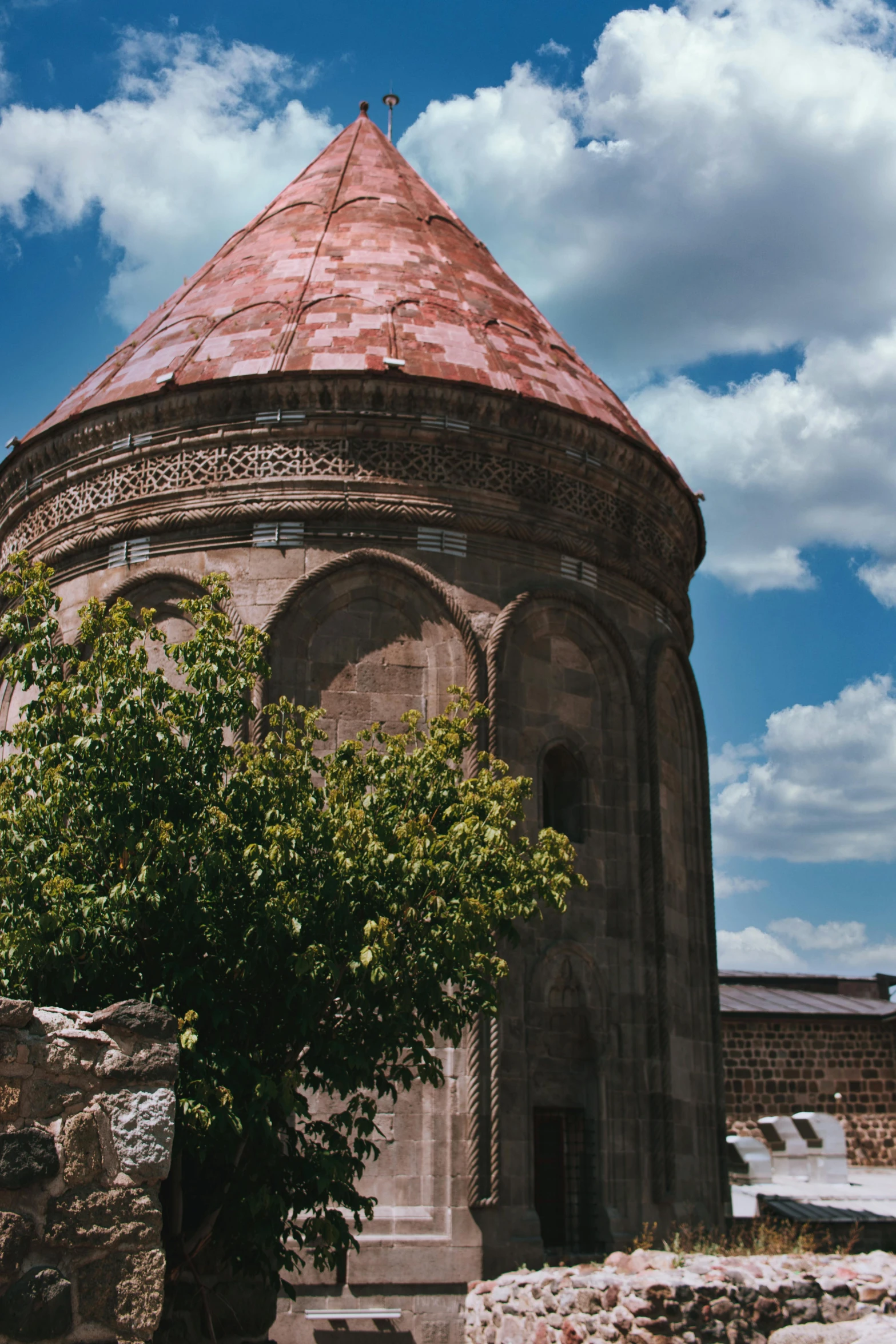 a round brick building under a blue sky with clouds