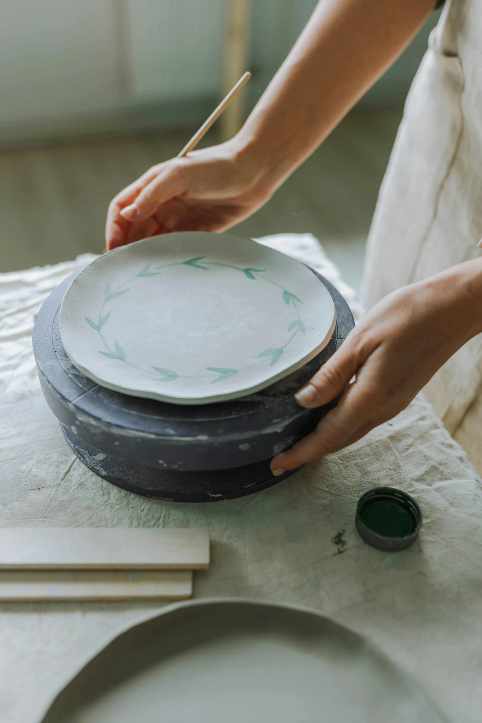 a person with paintbrush painting the white plate