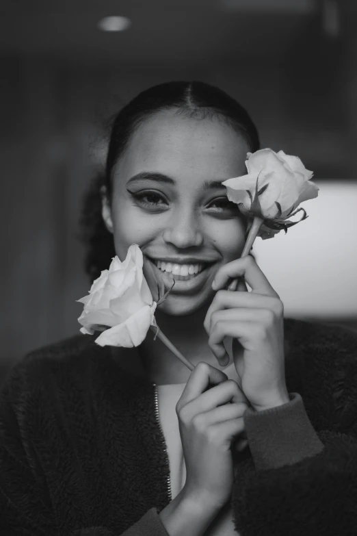 an attractive woman holding two flowers in front of her face