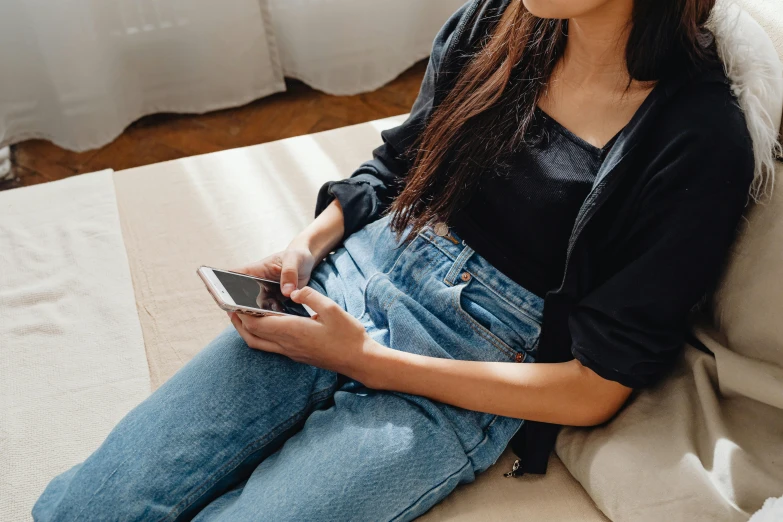 a woman holding a smart phone and sitting on a couch