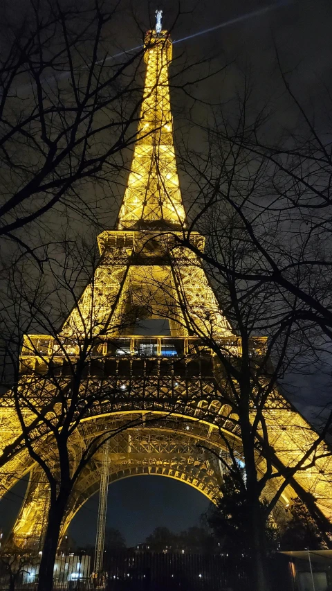 the eiffel tower at night with trees and lights in the background