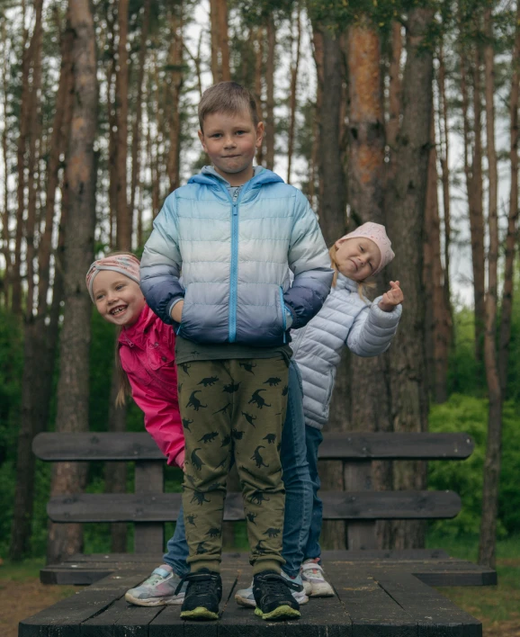 two young children are standing on a bench