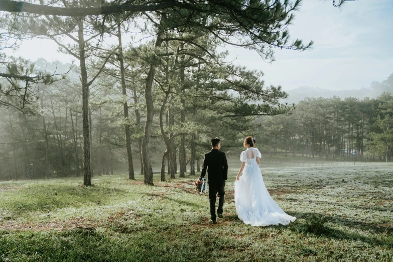 a bride and groom walk through the woods together