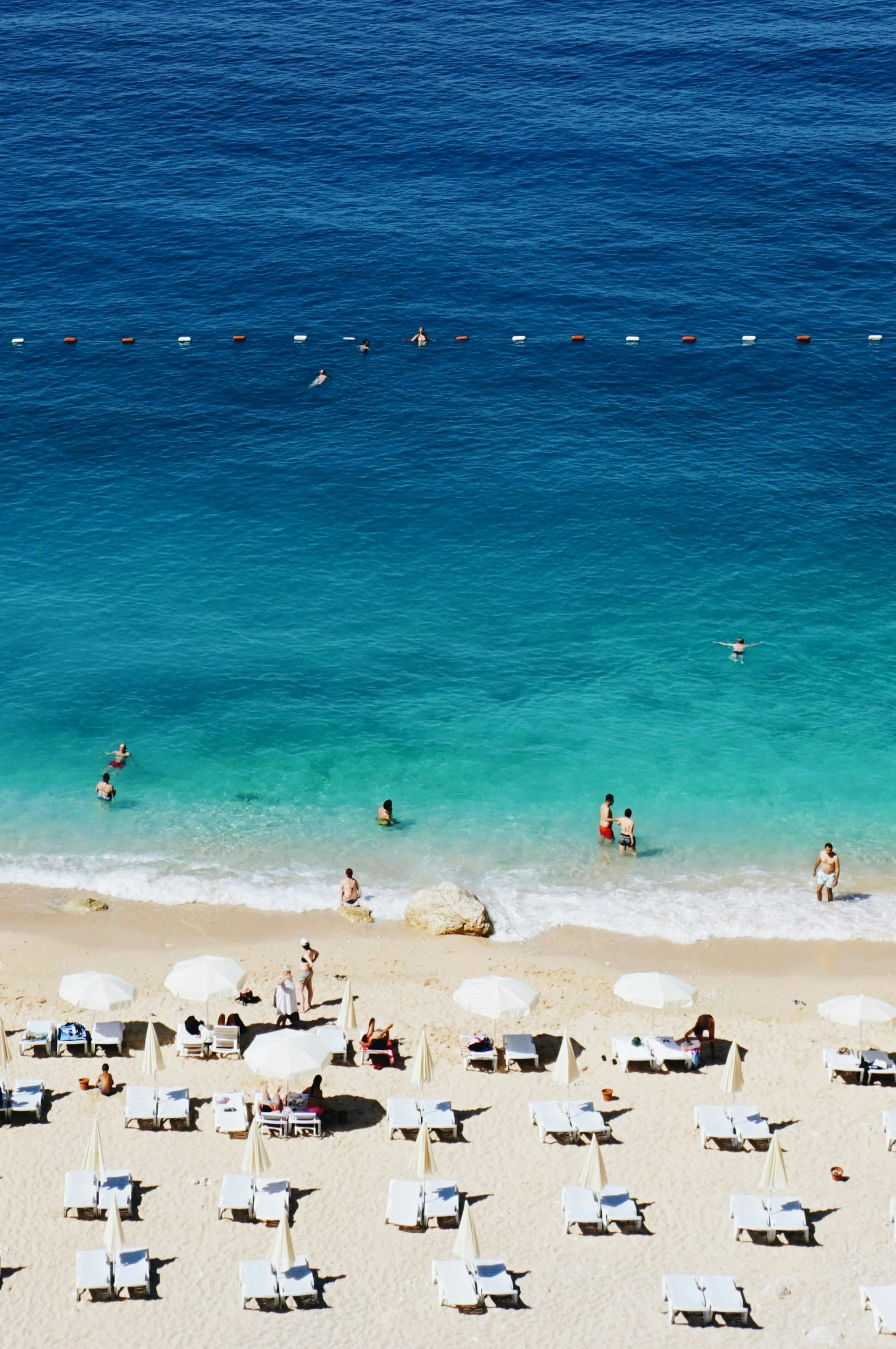 people enjoy the sun on a sandy beach with chairs and umbrellas