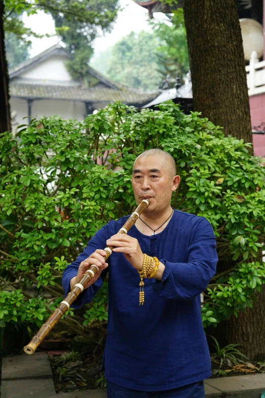 a man holding an instrument by a tree