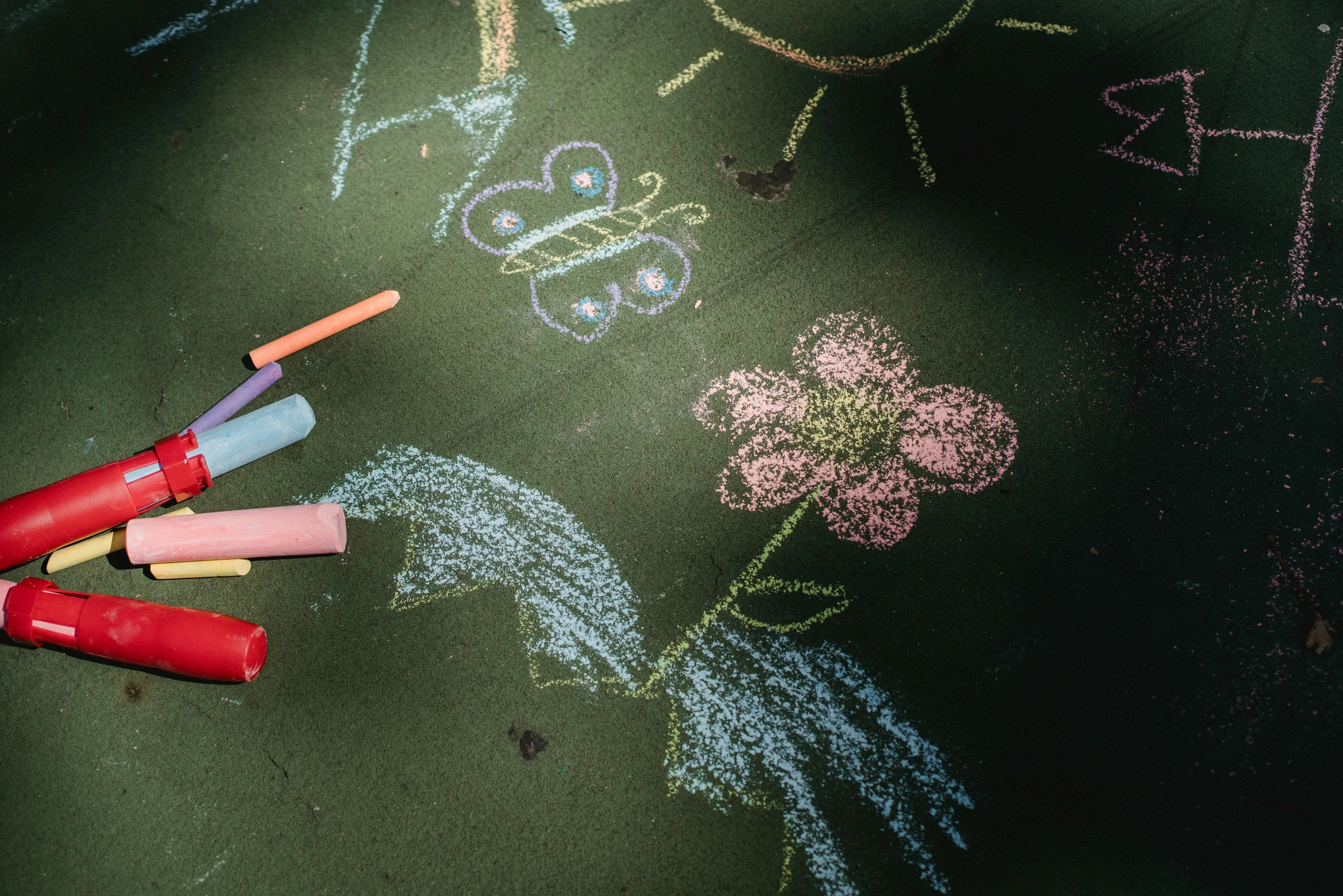 crayon and markers lay on chalk with some flowers