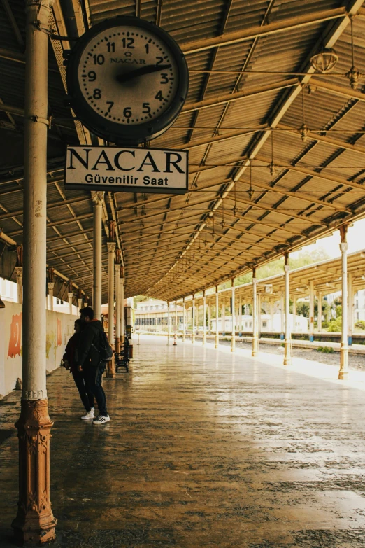 a man walking down the sidewalk underneath an awning with a clock