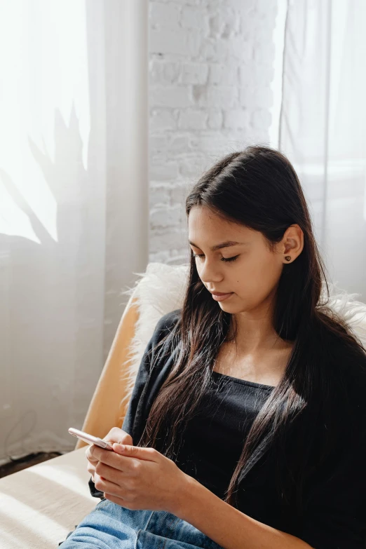 a girl sitting on the couch looking at her cell phone