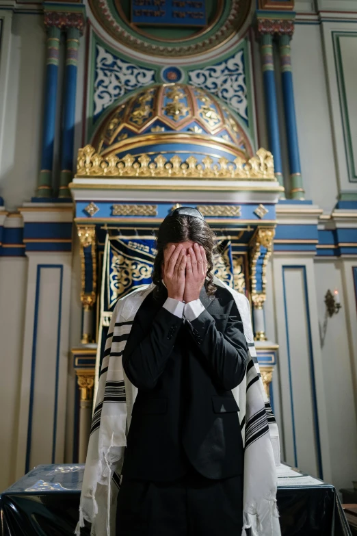 a priest has his hands on his head while covering his eyes