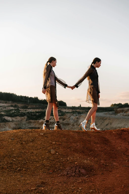 two s standing on top of a hill holding hands