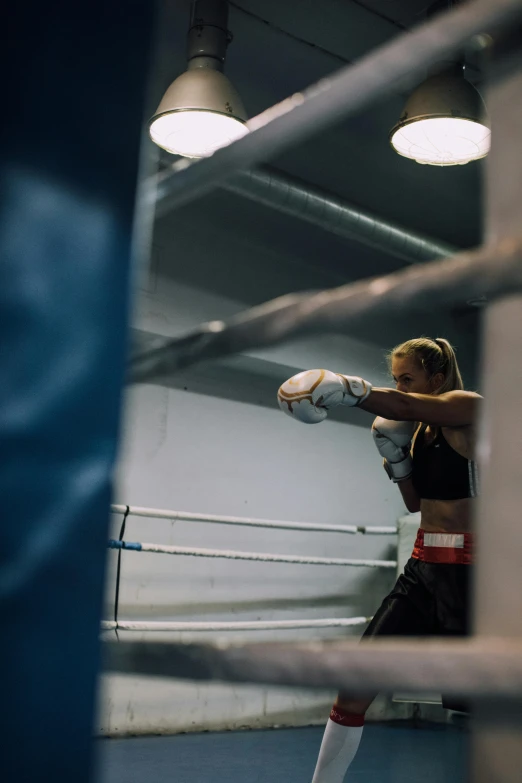 a woman standing next to boxing rings wearing gloves