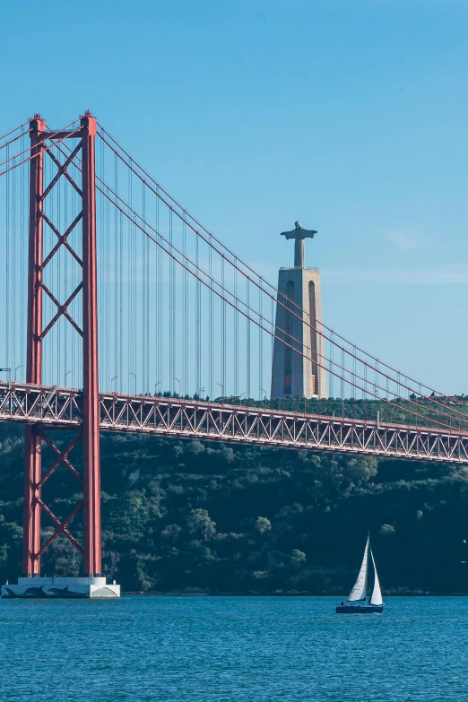 a sailboat and sailboat are sailing underneath a large bridge