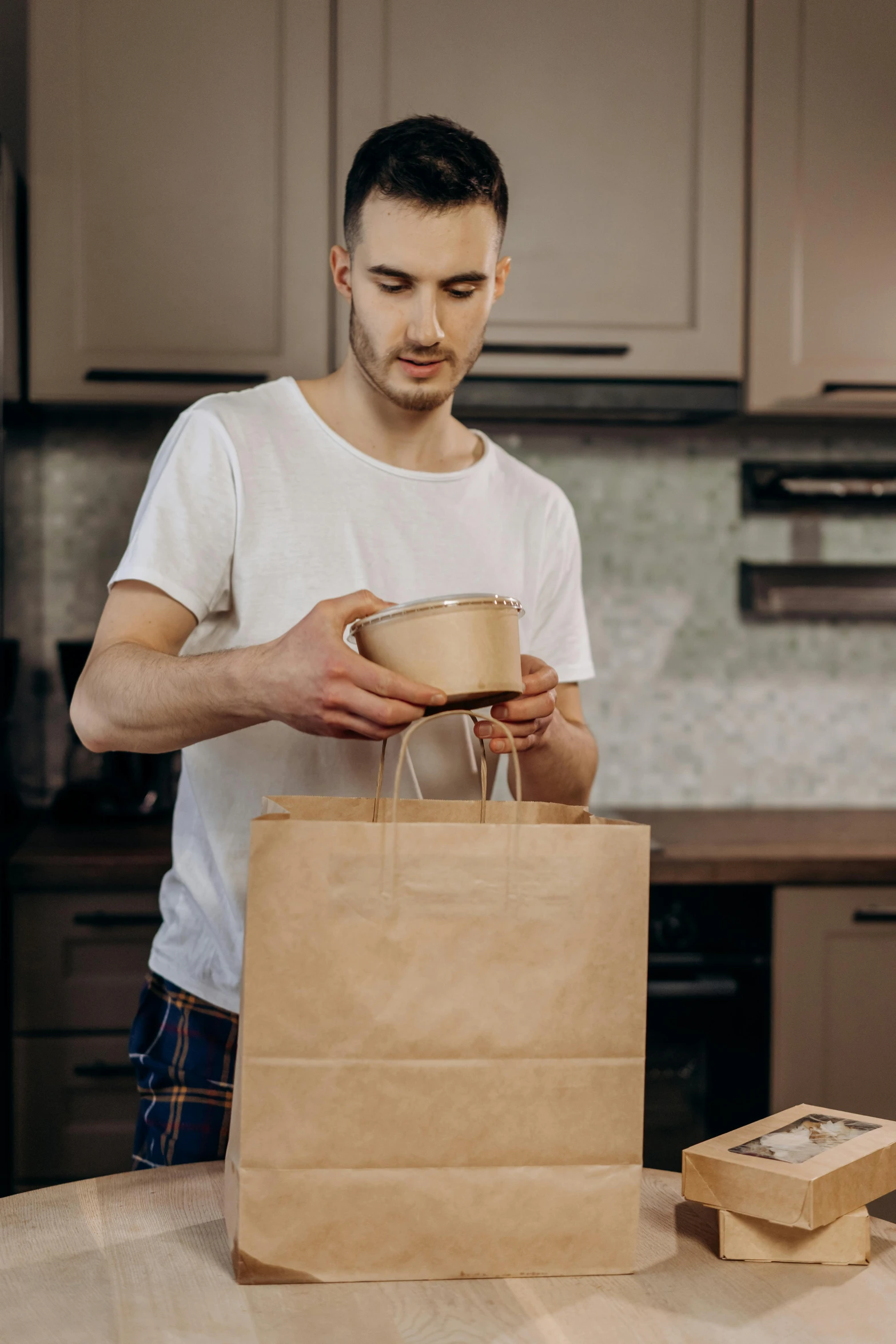 a man wearing white shirt holding a brown paper bag over a paper bag