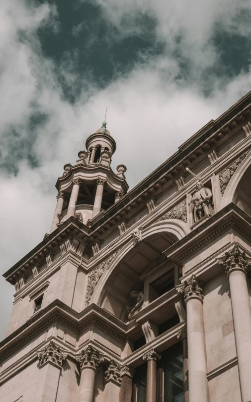 large stone building with a clock on top and cloudy sky