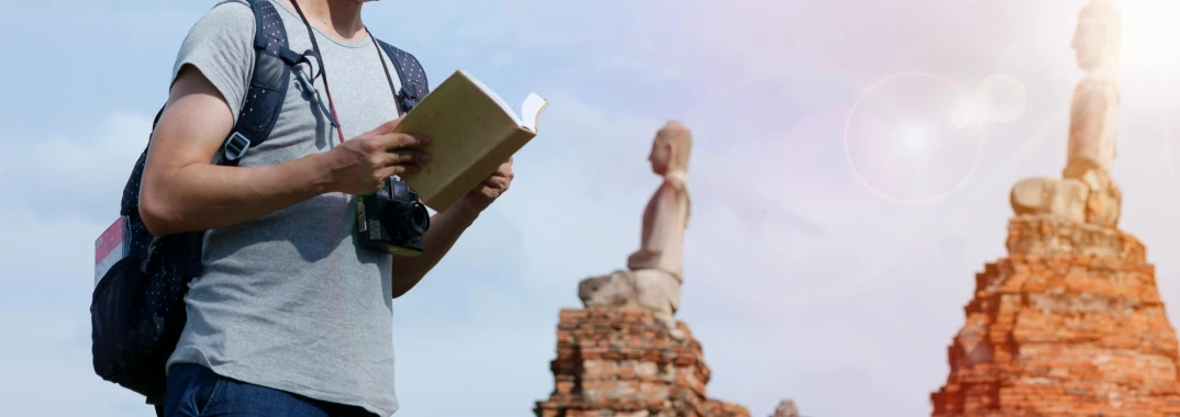 a woman holding a book next to a statue