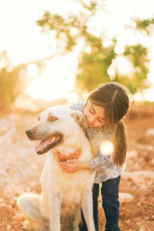 a little girl with her dog in front of some trees