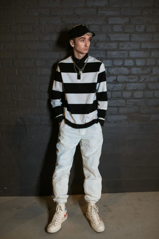 a young man standing in front of a brick wall