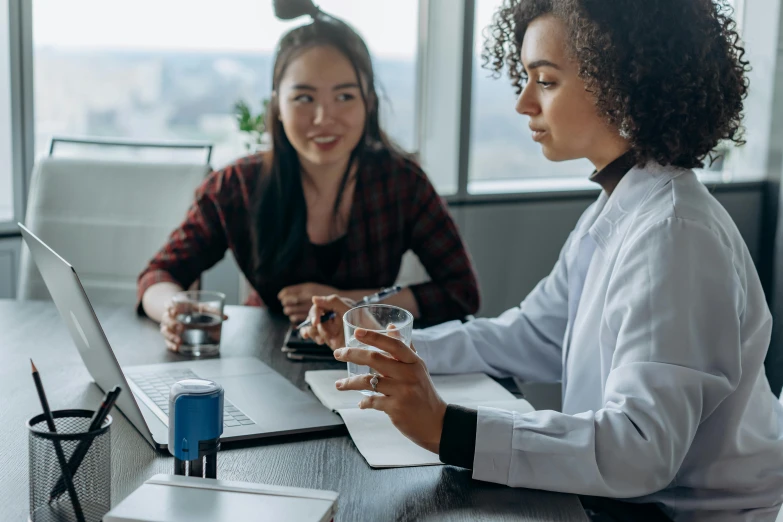 two woman at table working on laptops