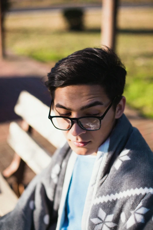 a young man wearing glasses while sitting on a bench