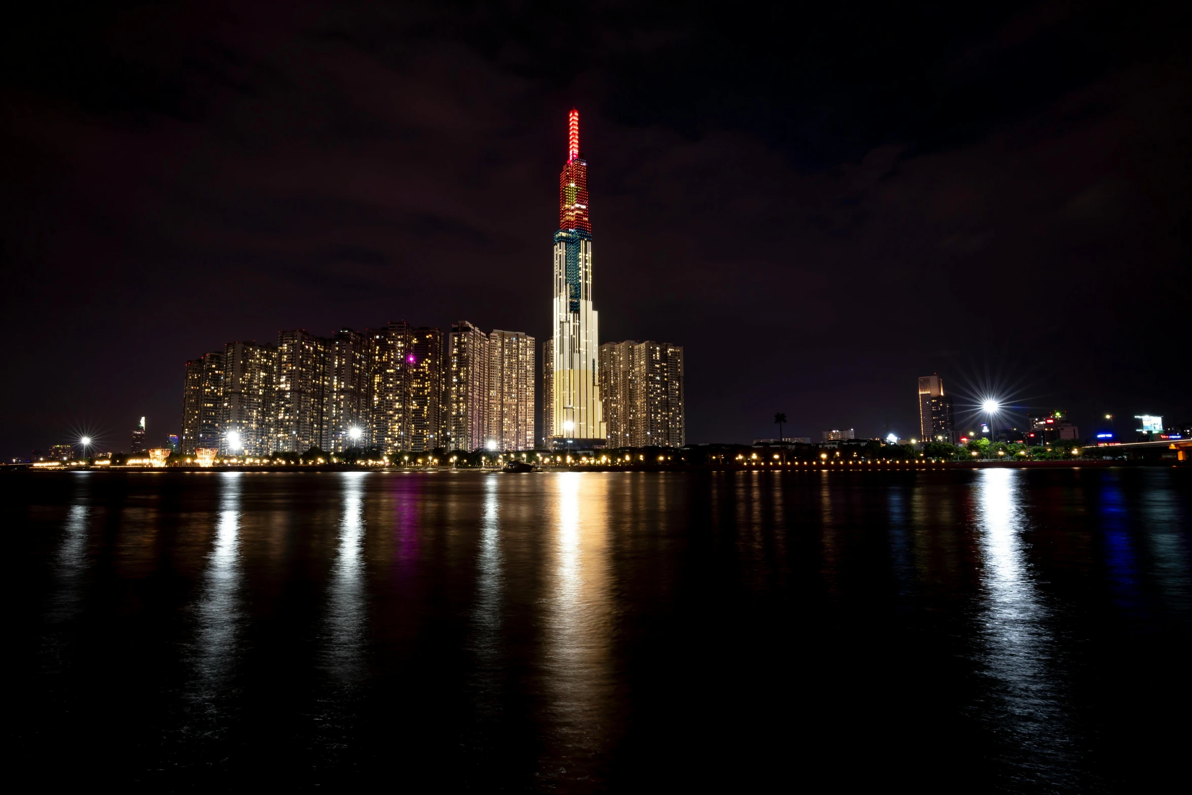 the dark city by the water at night is reflected in the water