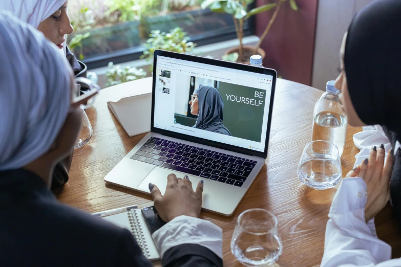 two people sitting at a table looking at the homepage on a laptop