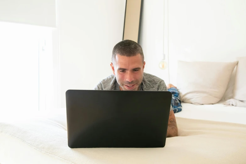 a man laying on the bed with a laptop computer