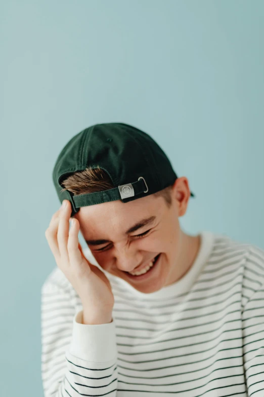 a young man smiling wearing a baseball cap