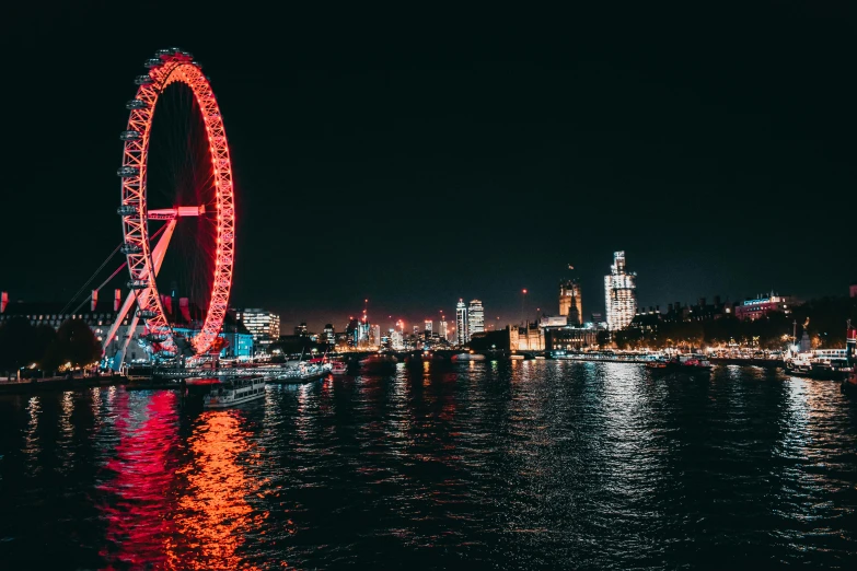 a ferris wheel lit up at night over the water