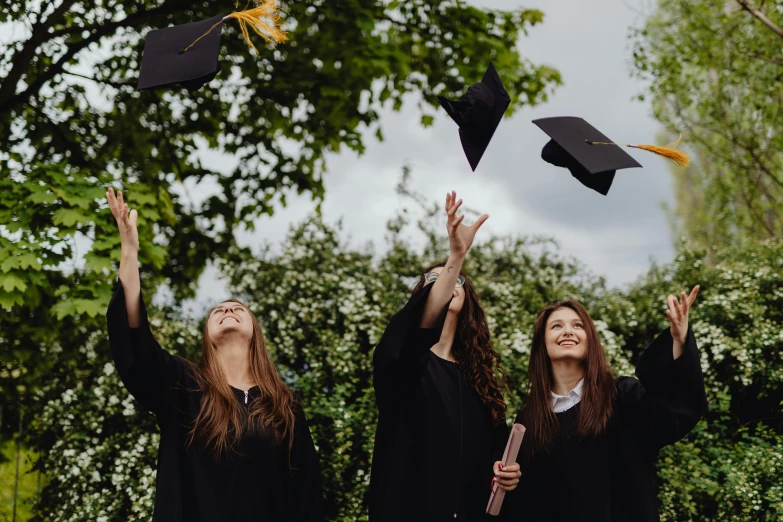 three girls tossing graduation hats in the air