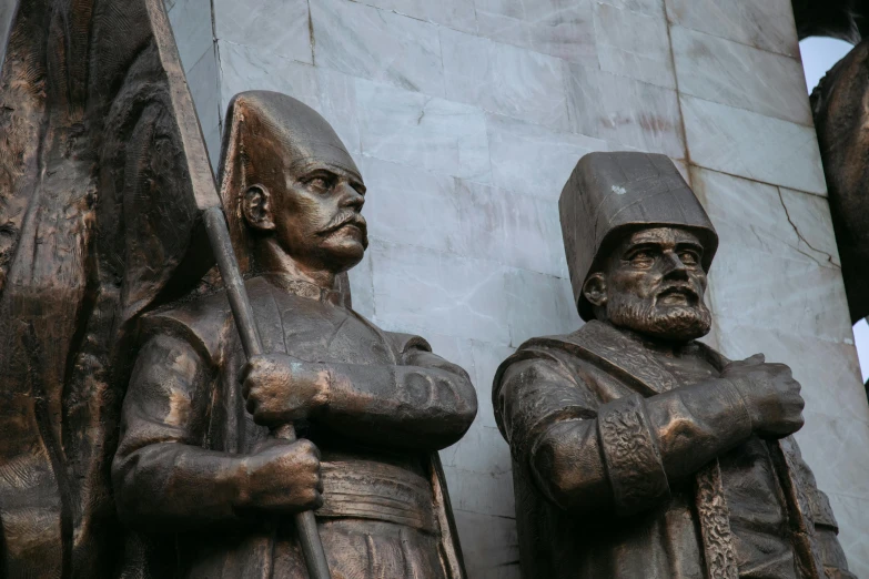 the three statues are wearing helmets and holding weapons