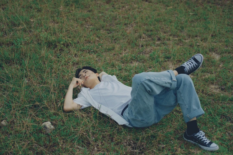 a man laying on the ground in the grass talking on a cell phone