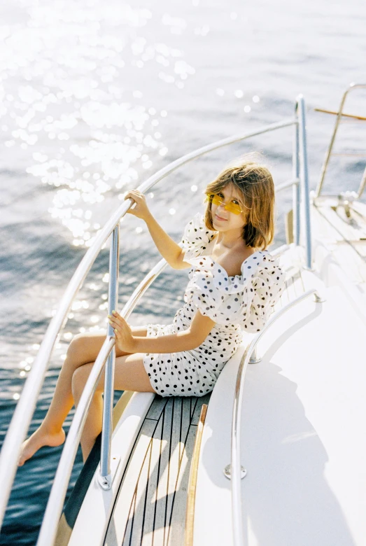 a girl riding on the bow of a boat, in a po