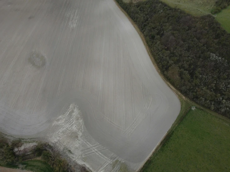 aerial view of a large open field surrounded by wooded area