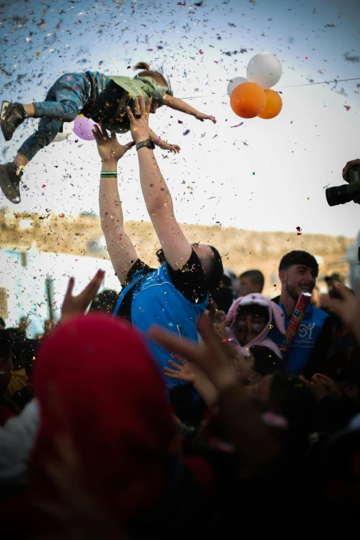 people throwing confetti and balloons into the air