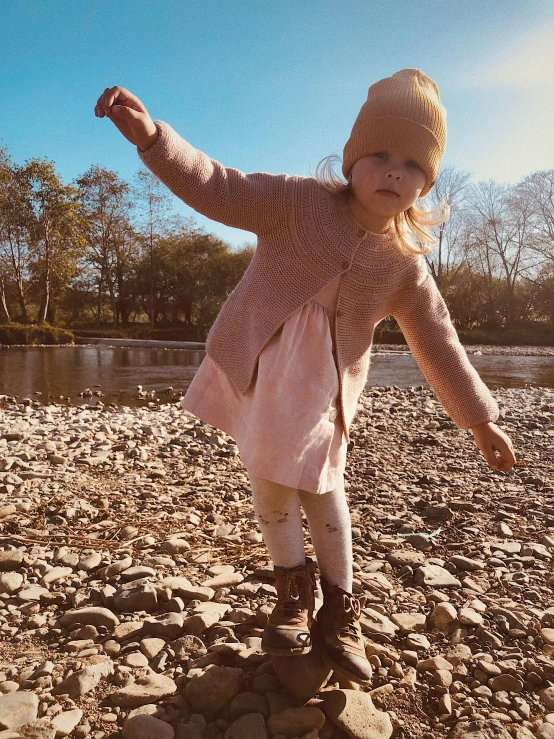 a girl is playing on the rocks by the river