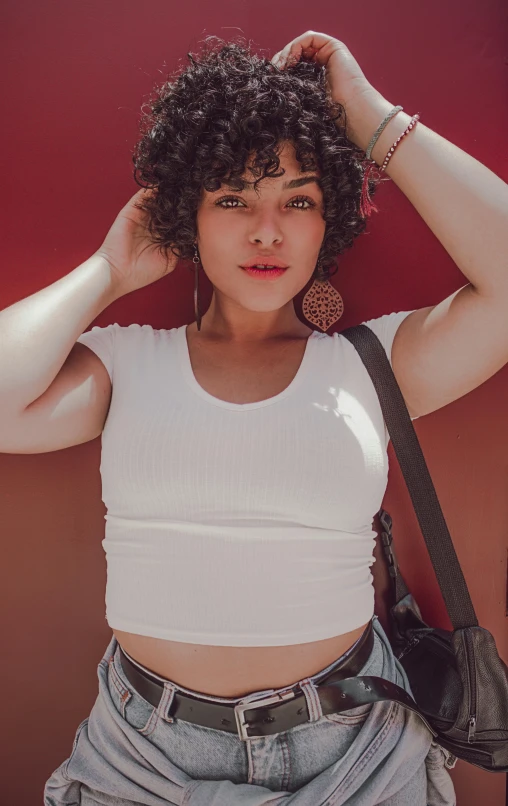 an attractive woman in a white shirt and jeans poses