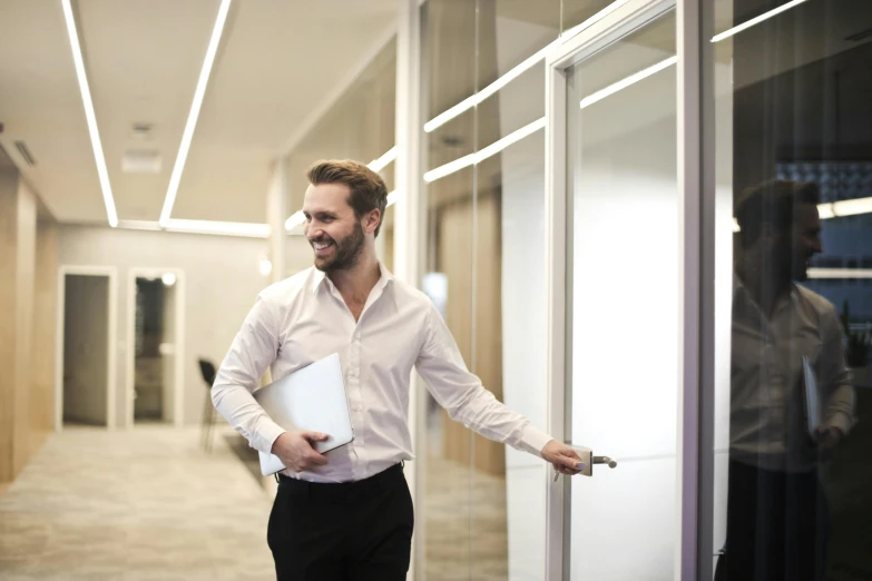 a man holding a binder walks out of a building