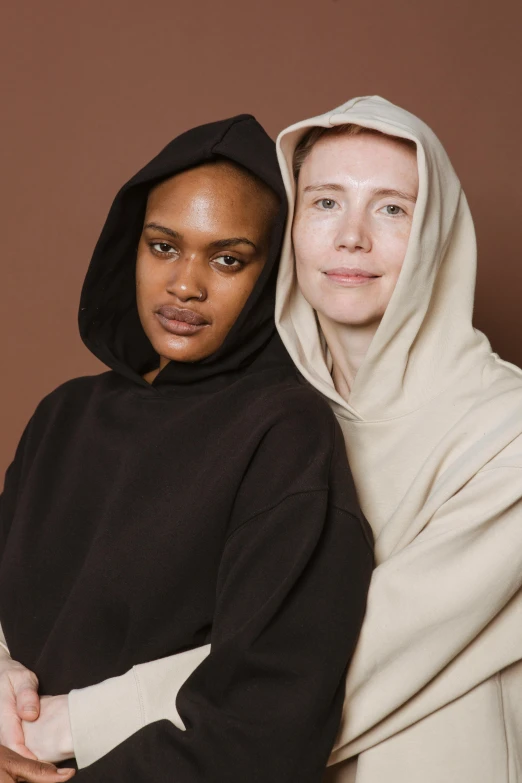 two woman standing next to each other wearing matching coats