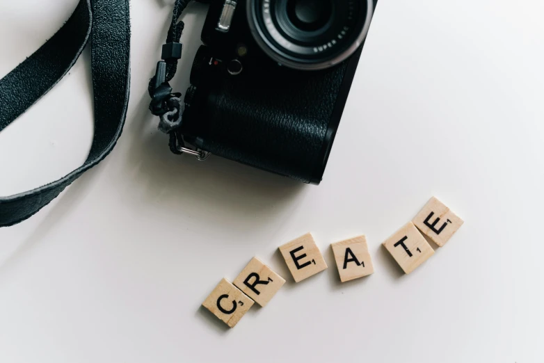 word made with scrabble blocks next to a camera