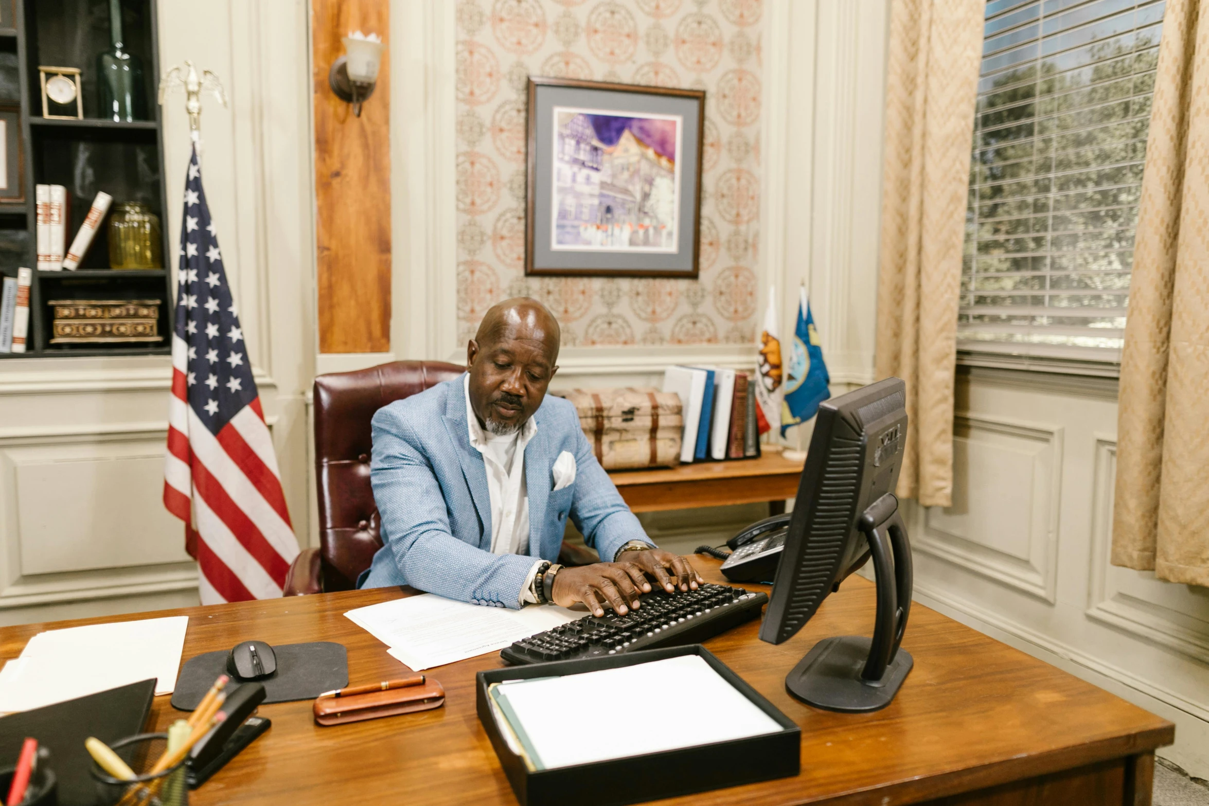 a person in an office with an american flag on the wall