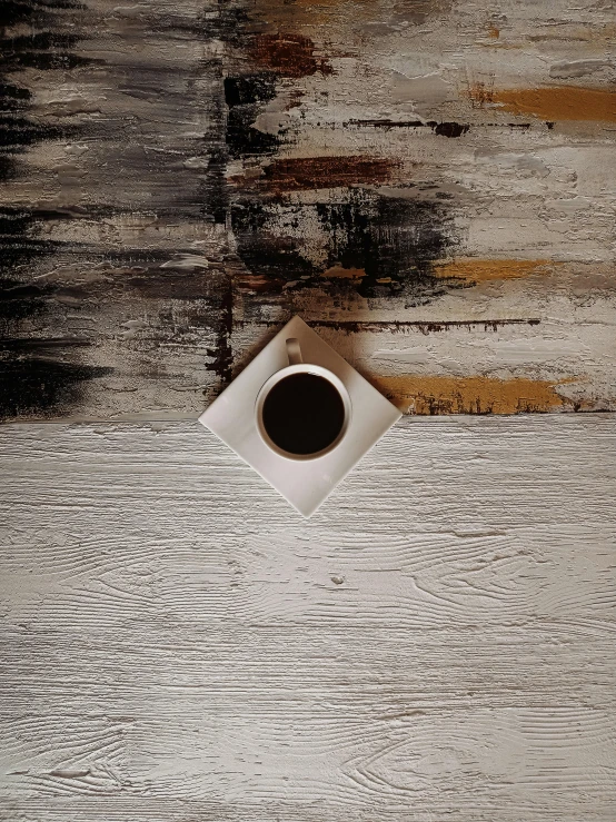 a cup of coffee next to a piece of wood