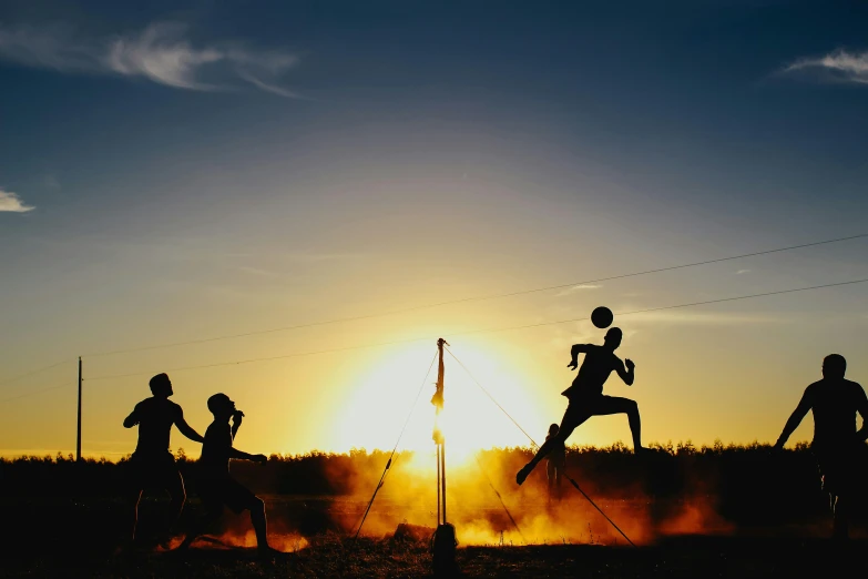 a group of runners running past the sun at sunset