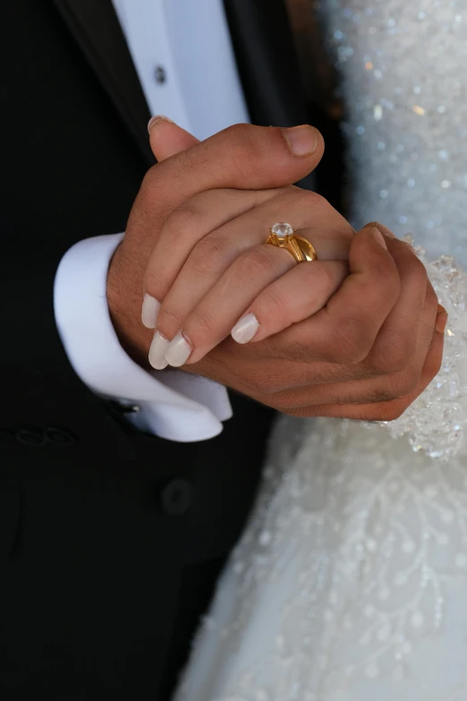 bride and groom holding hands together with wedding rings