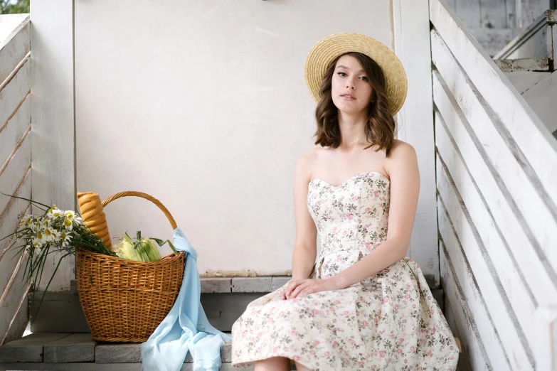 a woman wearing a straw hat is sitting on some steps