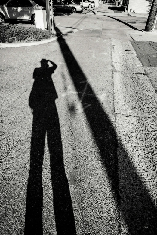 a shadow of a person standing on the sidewalk of a city street