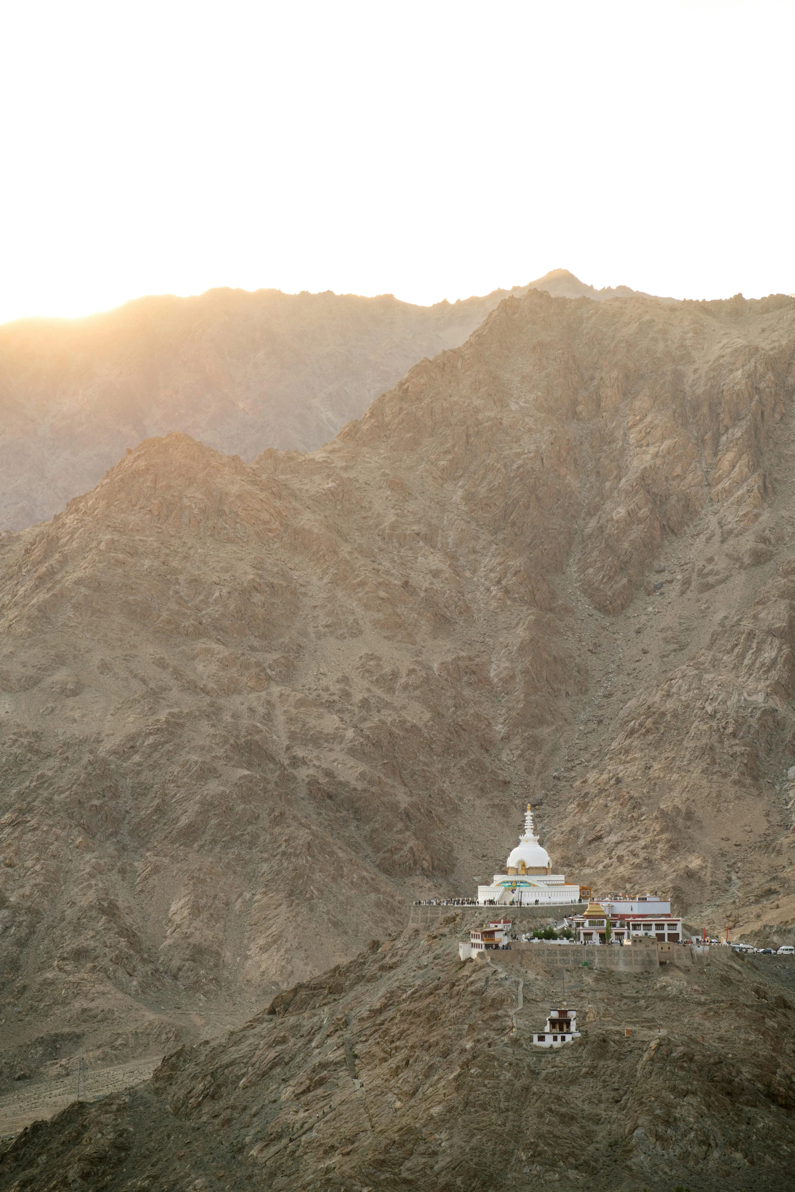 a mountain and house sit in the foreground with other mountains in the background