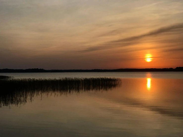 a large body of water with the sun setting over it