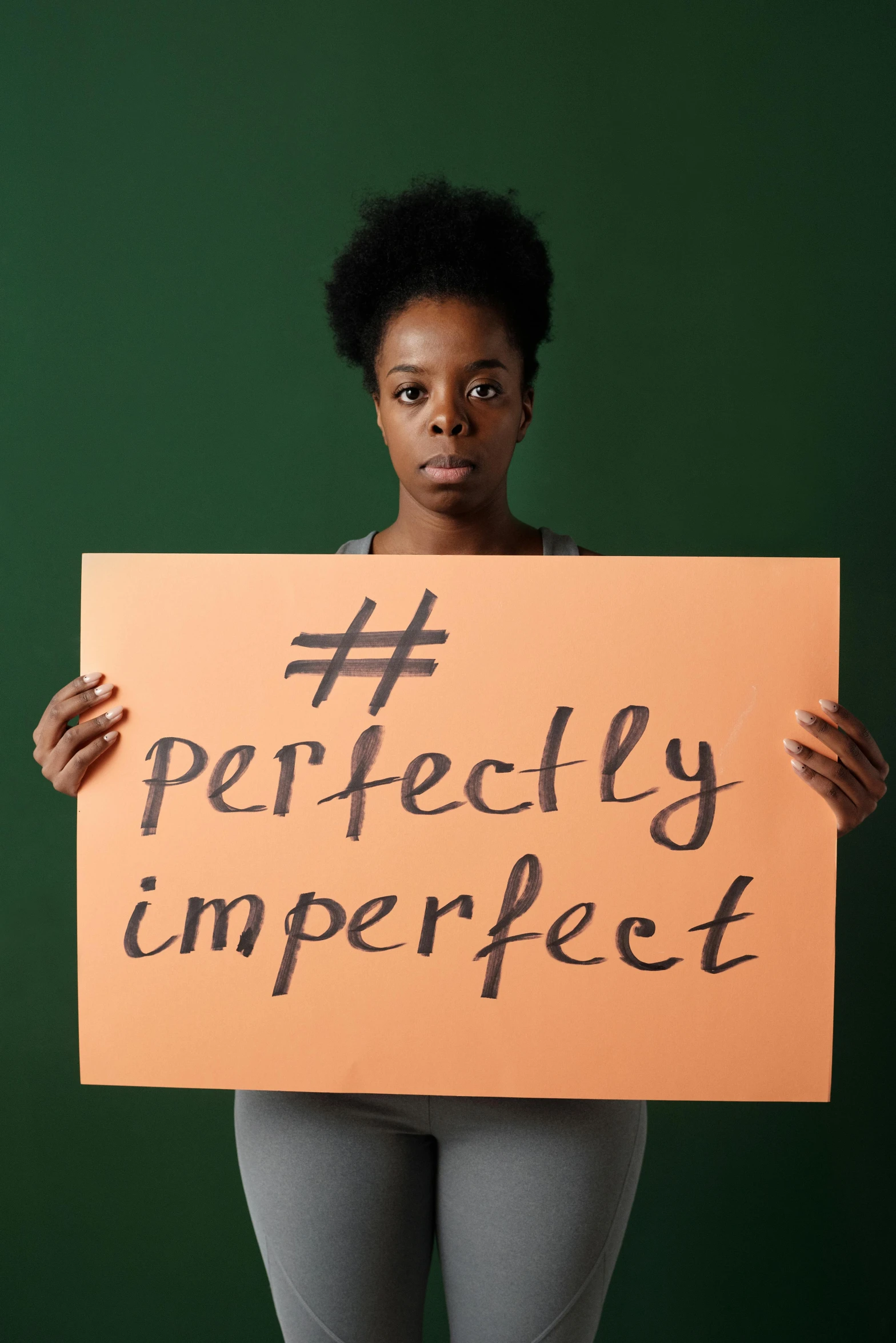 a woman holding up a sign saying perfectly imperfecteett