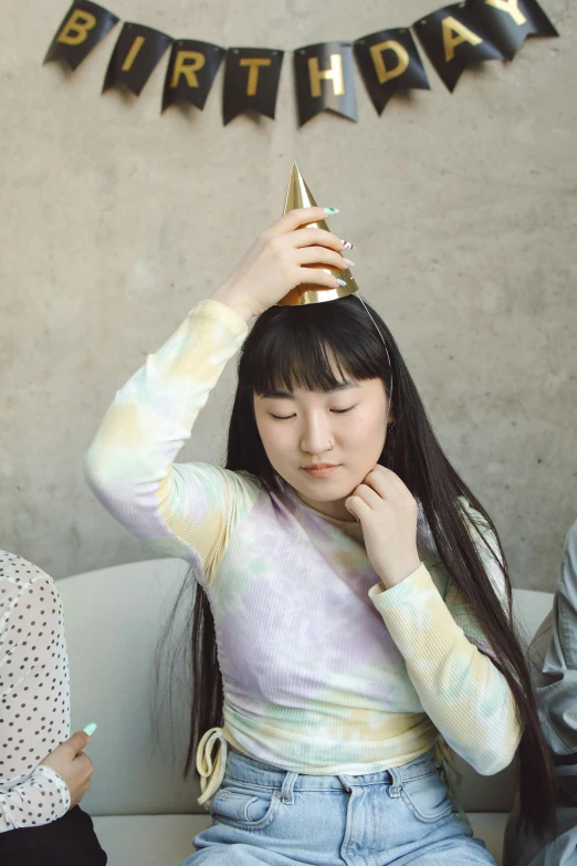 a girl in a birthday hat is sitting on a couch