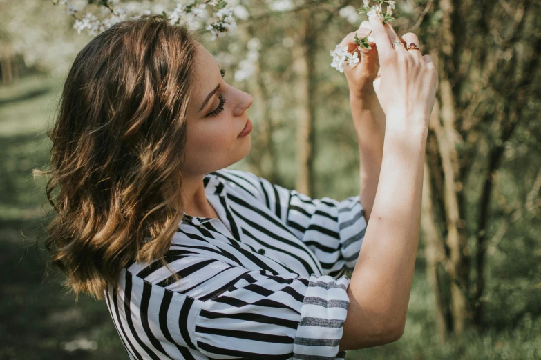 the woman is standing by the tree with flowers